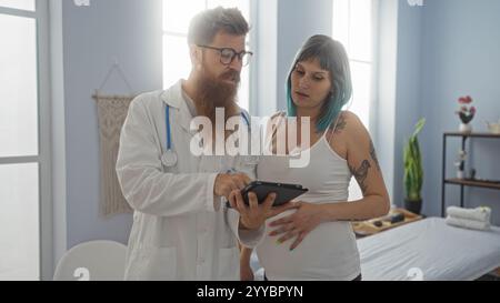 Femme enceinte consultant avec un médecin masculin dans la salle de clinique tout en examinant les informations sur comprimé, soulignant les soins de grossesse et la consultation médicale Banque D'Images