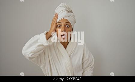 Femme surprise en peignoir avec serviette sur la tête isolé sur fond blanc montrant le choc ou l'étonnement Banque D'Images