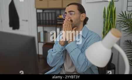 Jeune homme avec moustache dans un bureau regardant stressé ou pensif avec les mains couvrant la bouche Banque D'Images