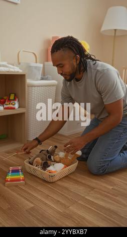 Jeune homme avec des tresses organisant des jouets dans un salon confortable, reflétant une atmosphère ordonnée et tranquille à la maison. Banque D'Images