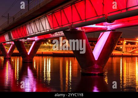 Un pont avec des lumières rouges qui brillent dessus. Les lumières sont sur le pont et l'eau les reflète Banque D'Images