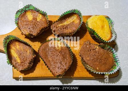 Une sélection de friandises fraîchement préparées est affichée sur une planche de bois. Les friandises présentent une texture marbrée avec un mélange de couleurs marron et jaune Banque D'Images