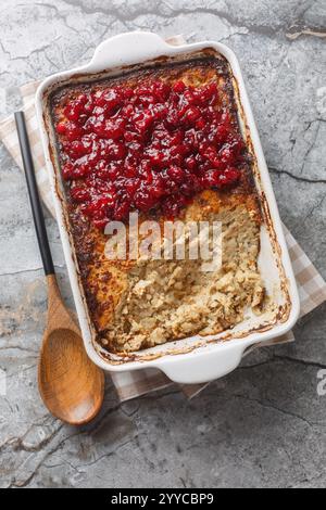 Casserole finlandaise Maksalaatikko faite de riz et foie avec sauce canneberge gros plan sur le plat de cuisson sur la table. Vue de dessus verticale Banque D'Images