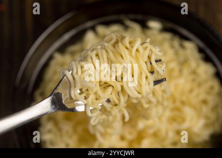 nouilles roulées aux œufs pendant la cuisson, détails des nouilles de farine dans un bol noir Banque D'Images