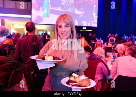 Berlin, Allemagne. 21 décembre 2024. Annemarie Eilfeld, chanteuse, sert des oies rôties aux personnes nécessiteuses et sans-abri. La 30ème fête de Noël de Frank Zander pour les sans-abri a lieu aujourd'hui à l'Hôtel Estrel. Crédit : Annette Riedl/dpa/Alamy Live News Banque D'Images