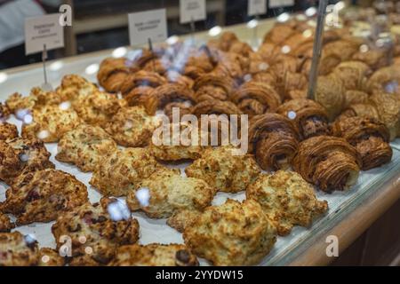 Vitrine avec différents desserts savoureux dans la boulangerie, gros plan. Différents types de pain et pâtisseries, croissants, biscuits exposés dans une boulangerie. Moderne Banque D'Images