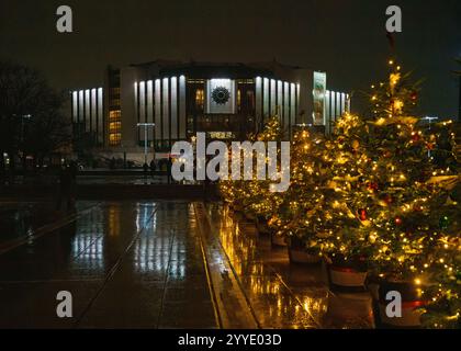 Vue nocturne du Palais National de la culture (NDK) à Sofia, Bulgarie, orné de lumières de Noël festives. Rangées d'arbres de Noël décorés Banque D'Images