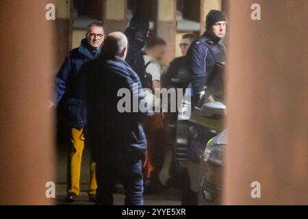Magdebourg, Allemagne. 21 décembre 2024. Un homme (M) est conduit à un véhicule de police dans la cour intérieure du Centre de Justice en présence de Horst Walter Nopen (l), procureur général du ministère public de Magdebourg. La veille, un chauffeur de voiture avait croisé un groupe de personnes au marché de Noël de Magdebourg. L'homme a été arrêté. Crédit : Christoph Soeder/dpa - ATTENTION : homme pixelisé pour des raisons légales/dpa/Alamy Live News Banque D'Images
