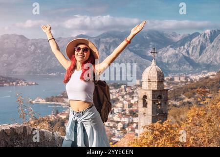 Heureux touriste avec sac à dos levant les bras profitant de la vue sur la baie de Kotor au Monténégro Banque D'Images