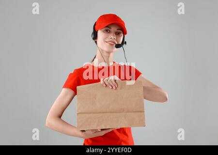 Travailleur de restauration rapide avec sac en papier sur fond gris Banque D'Images