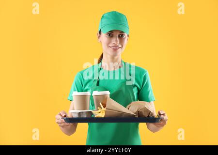 Travailleur de la restauration rapide tenant le plateau avec commande sur fond orange Banque D'Images