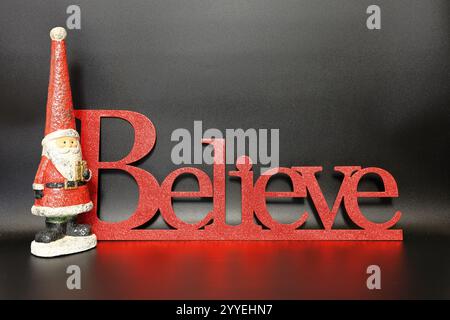 Le mot croire à côté de Santa clause avec un fond noir sans couture propre Banque D'Images