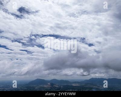 Un ciel nuageux avec une montagne en arrière-plan. Le ciel est principalement nuageux avec quelques taches de bleu Banque D'Images