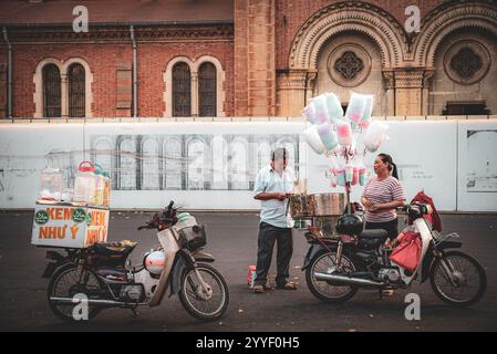 Un homme et une femme sont debout à côté d'une moto. L'homme regarde son téléphone Banque D'Images
