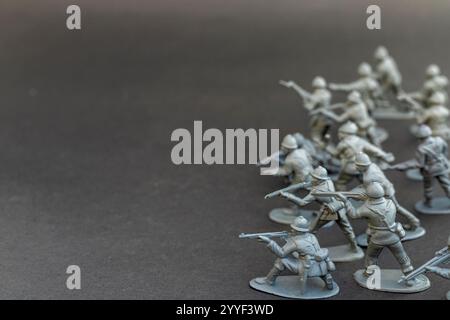 Groupe de soldats jouets gris en position de bataille sur fond sombre Banque D'Images