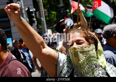 Melbourne, Australie. 22 décembre 2024. Une manifestante lève le poing pendant le rassemblement. Les manifestants ont organisé un rassemblement au CBD de Melbourne, appelant à des sanctions contre Israël ce Noël pour mettre fin à l'agression sioniste et honorer les vies perdues au moyen-Orient. (Photo de Ye Myo Khant/SOPA images/Sipa USA) crédit : Sipa USA/Alamy Live News Banque D'Images