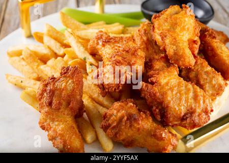 Vue rapprochée d'un plateau d'amuse-gueule d'ailes de poulet frites et de frites. Banque D'Images