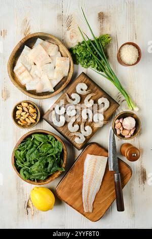 Le comptoir de cuisine présente un assortiment de fruits de mer frais et de légumes vibrants, y compris des crevettes, des filets de poisson et des légumes feuillus, tous mis en place pour un Banque D'Images