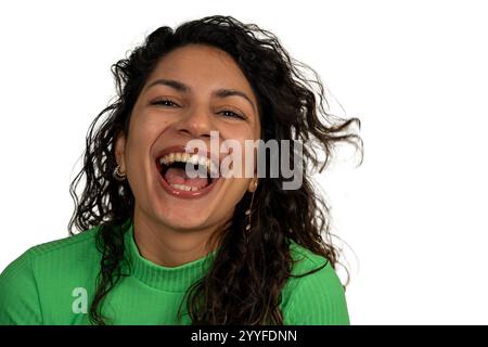 Portrait studio d'une jeune femme latine joyeuse riant la bouche ouverte, montrant des dents, portant un pull vert à col roulé Banque D'Images