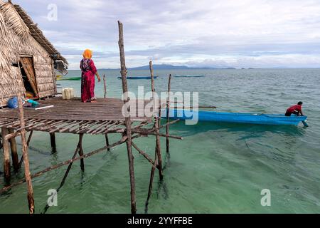 Femme en vêtements traditionnels de la tribu bajau sur un porche d'une maison en bois sur pilotis au milieu d'une mer près de l'île de Muna, sulawesi, indonésie Banque D'Images