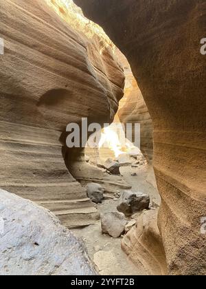 Un canyon étroit avec un sentier rocheux qui le traverse. Le soleil brille à travers les rochers, créant une atmosphère chaleureuse et accueillante Banque D'Images