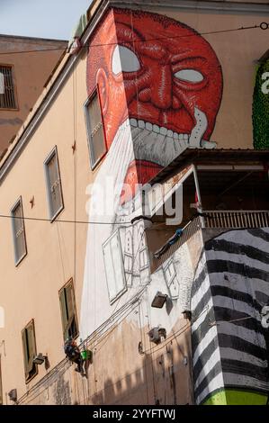 Street art du célèbre artiste Blu dessiné en direct sur la façade de l'ancien hôpital psychiatrique judiciaire (OPG) dans la via Matteo Renato Imbriani à Naples. Banque D'Images