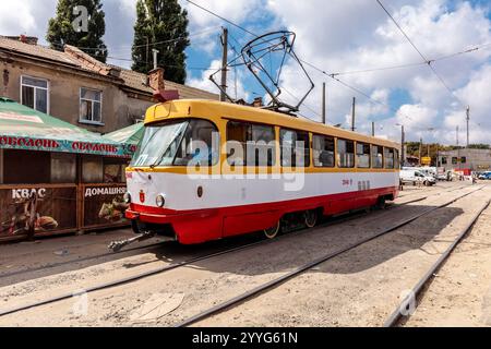 Un train jaune et rouge est stationné sur les voies. Le train est entouré de bâtiments et d'arbres Banque D'Images