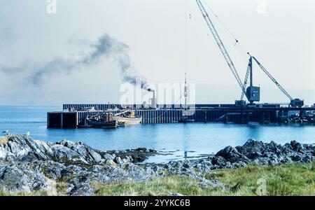 Photo historique de bateaux de pêche amarrés à la jetée avec des grues à Campbeltown, Argyll, Écosse, Royaume-Uni dans les années 1960 Banque D'Images