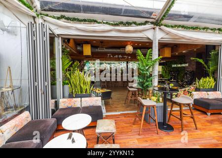 Bar moderne sur le toit avec plantes tropicales, sièges élégants et décoration intérieure ouverte surplombant la ville sous verrière. New York. ÉTATS-UNIS. Banque D'Images