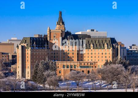 Un grand bâtiment en briques avec un toit vert et une grande tour. Le bâtiment est entouré d'arbres et de neige Banque D'Images