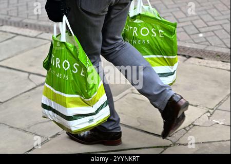 Cambridge, Angleterre, 22-décembre-2024, deux sacs Carrier de marque Waitrose transportés dans la rue de la ville Banque D'Images