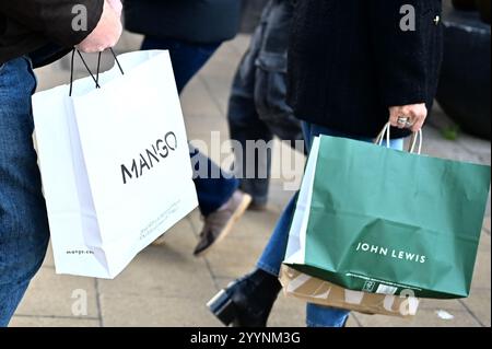 Cambridge, Angleterre, 22-décembre-2024, sac de marque Mango et John Lewis transporté dans la rue de la ville Banque D'Images