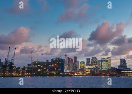 L'horizon de Canary Wharf à Londres est illuminé pendant Noël, avec des gratte-ciel reflétant la Tamise et le téléphérique Emirates Air Line Banque D'Images