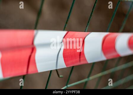 Ruban adhésif rouge et blanc rayé tendu à travers une rue de la ville, marquant une zone interdite ou une zone de construction dans un pâté de maisons de la ville. Banque D'Images