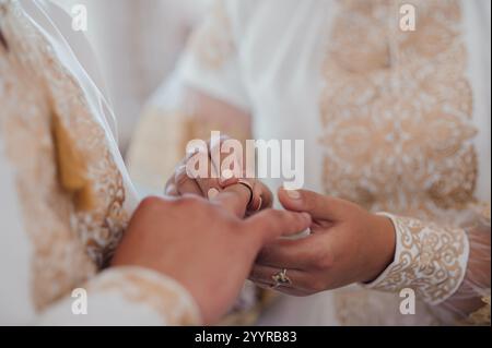 Cérémonie d'échange d'anneaux de mariage élégante capturée dans une lumière naturelle douce. Banque D'Images