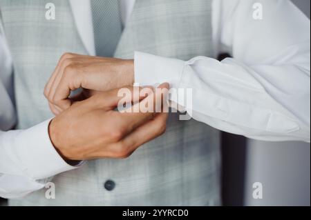 Élégant Groom ajuster ses boutons de manchette dans une tenue élégante. Banque D'Images