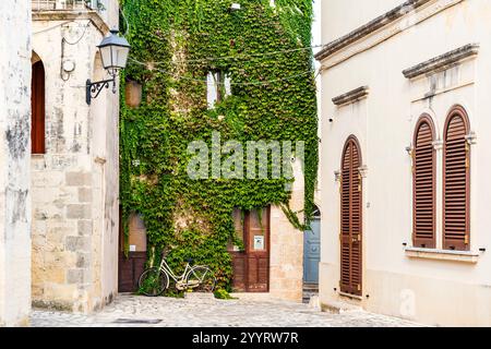 Une place pittoresque avec un mur couvert de lierre et un vélo dans le centre historique de la province d'Otrante de Lecce, région du Salento, région des Pouilles, Italie Banque D'Images