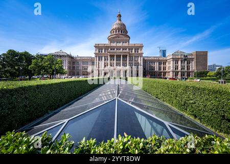 Le bâtiment du Capitole de l'État à Austin, Texas, se prélasse sous un ciel d'été lumineux, son dôme emblématique brillant sur un fond bleu vif, symbole du Texas. Banque D'Images