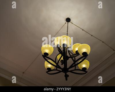 Lustre moderne noir accroché au plafond blanc au coin de la pièce, lumière jaune chaude ou ampoules accrochées à l'intérieur, bâtiment de style loft intérieur. Vintag Banque D'Images