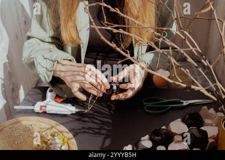 Femme méconnaissable créant une décoration de vacances de Pâques à partir de coquille d'œuf. DIY faites-le vous-même étape par étape instruction. Vacances de préparation artisanale Banque D'Images