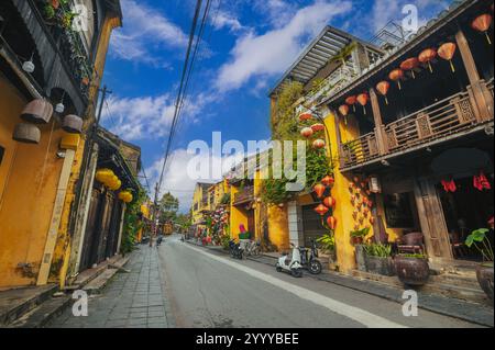 Rues avec de vieilles maisons jaunes traditionnelles décorées de lanternes de papier dans la vieille ville de Hoi an au Vietnam pendant la journée. Banque D'Images