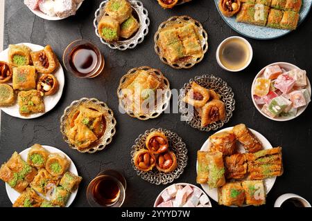 Des bonbons traditionnels du moyen-Orient servis dans différentes assiettes avec des boissons dans un cadre cosy lors d'un rassemblement festif Banque D'Images