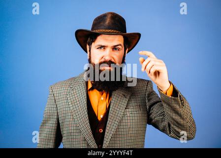 Beau cow-boy hipster à l'ancienne dans un chapeau de cow-boy. Des cowboys américains. Portrait d'homme barbu portant un chapeau de cow-boy. Style cow-boy. Cow-boy rétro Banque D'Images