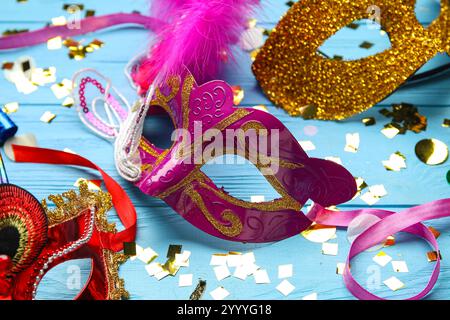 Beaux masques de carnaval avec cornes de fête et confettis sur fond en bois bleu. Gros plan Banque D'Images