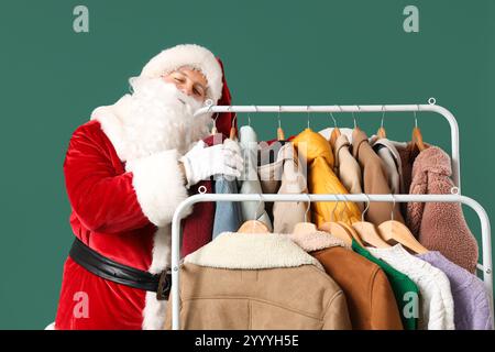 Père Noël et rack avec différents vêtements sur fond vert Banque D'Images