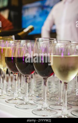 Une collection magnifiquement agencée de verres à vin remplis de vins rouges et blancs, sur une nappe blanche. L'image capture une scène perf élégante Banque D'Images