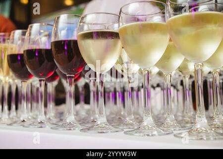 Une collection magnifiquement agencée de verres à vin remplis de vins rouges et blancs, sur une nappe blanche. L'image capture une scène perf élégante Banque D'Images