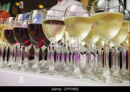 Une collection magnifiquement agencée de verres à vin remplis de vins rouges et blancs, sur une nappe blanche. L'image capture une scène perf élégante Banque D'Images