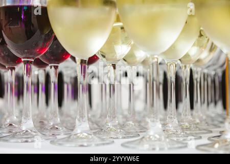 Une collection magnifiquement agencée de verres à vin remplis de vins rouges et blancs, sur une nappe blanche. L'image capture une scène perf élégante Banque D'Images