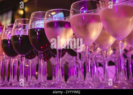 Une collection magnifiquement agencée de verres à vin remplis de vins rouges et blancs, sur une nappe blanche. L'image capture une scène perf élégante Banque D'Images